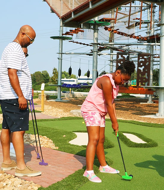 Young girl putting on the mini golf course at RYZE