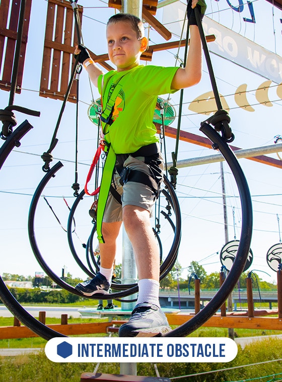 boy on ropes course ring element