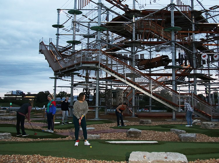 several people playing putt putt golf in the evening with the Adventure Tower in the background at Ryze Adventure Park