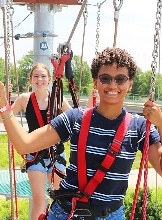 teenage boy and girl having a blast as they play on the aerial ropes course in Maryland Heights