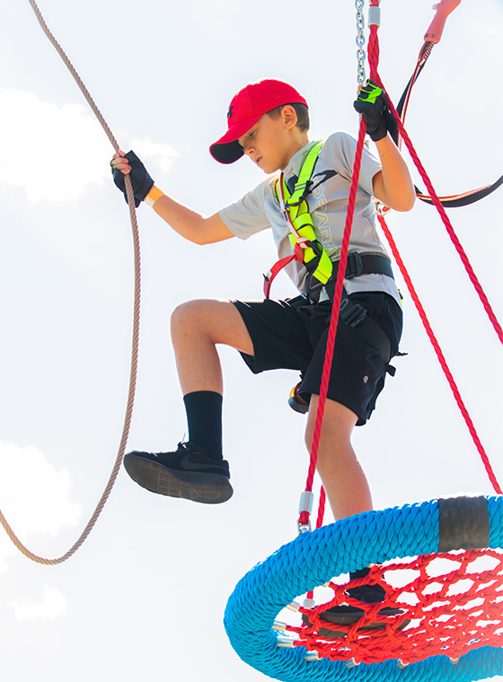 Young boy on obstacle and high ropes course take a step in Maryland Heights