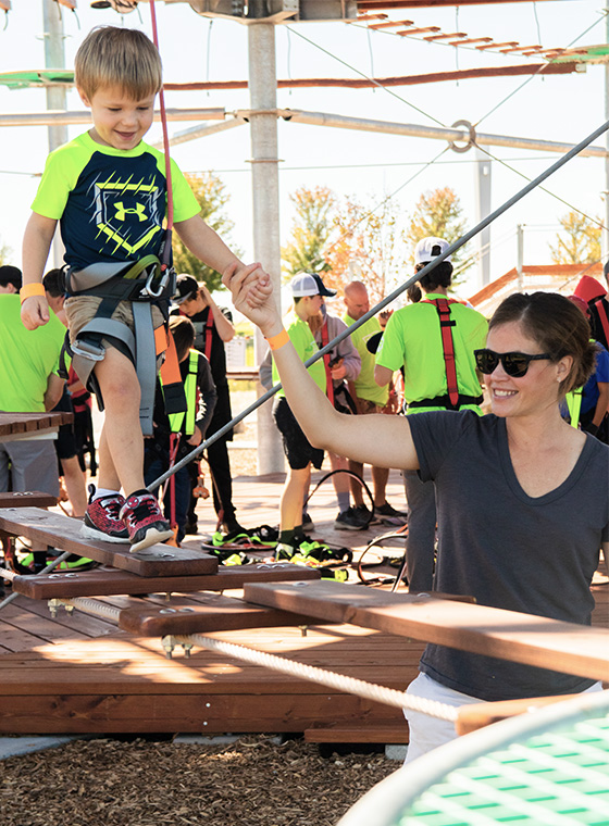 Mom helping kid on Little Ninja Ropes Course