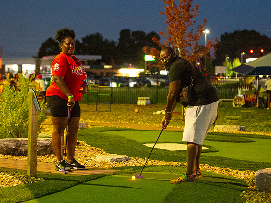 couple playing glow minigolf during date night event on ropes course
