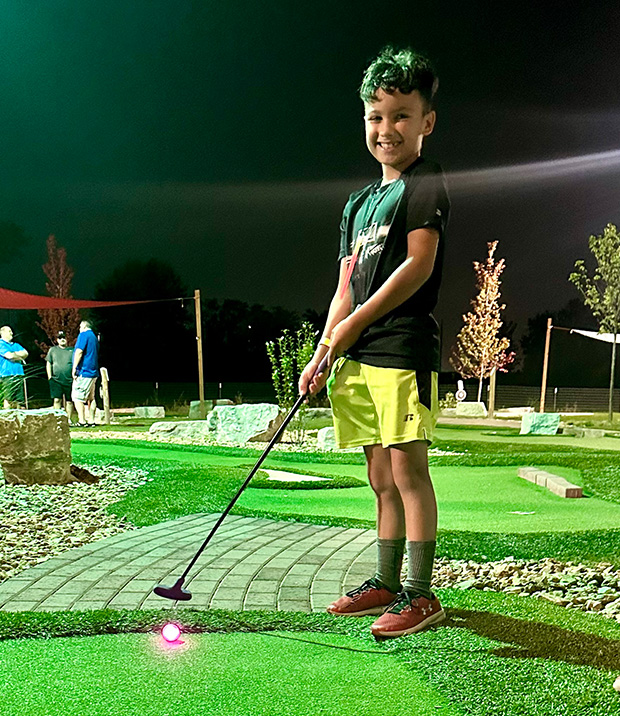 Young boy playing Glow in the Dark Golf in Maryland Heights, MO