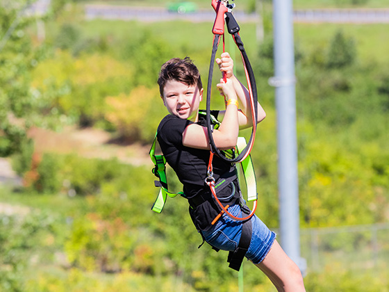 Boy on a zipline on a ropes course in St. Louis, MO