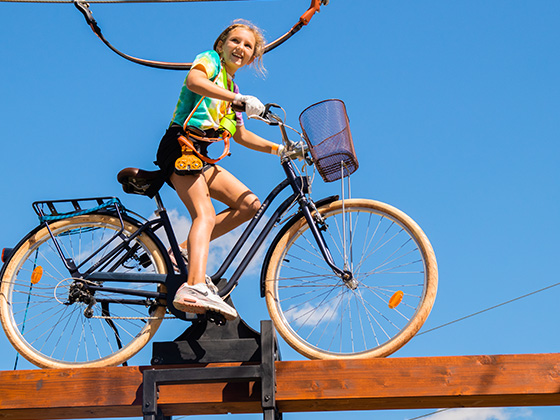 Smiling girl on bike crossing on the adventure tower